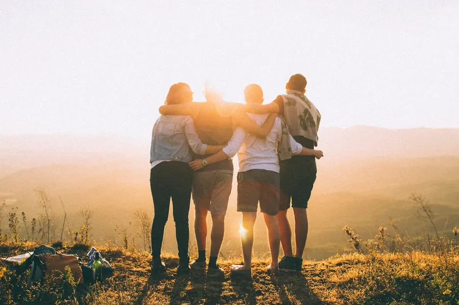 Amigos e família abraçados ao pôr do sol